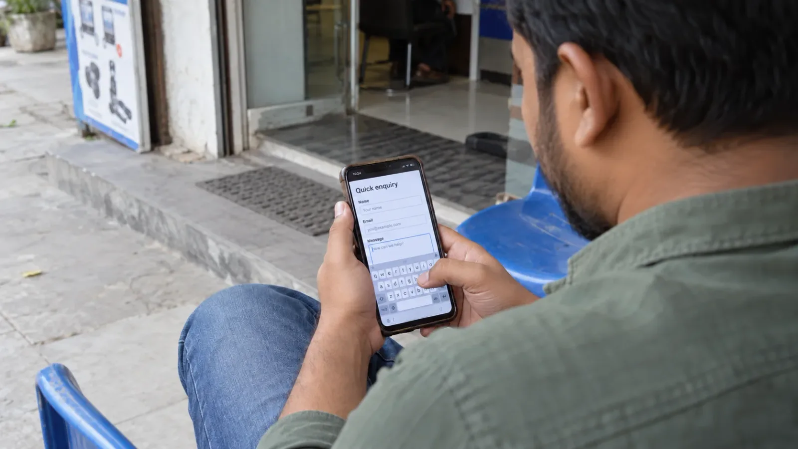 A seated customer completing a phone enquiry outside a local business